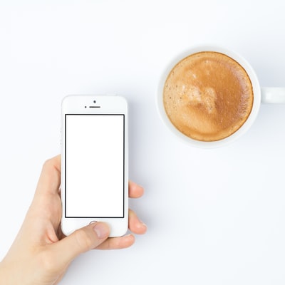 白色陶瓷杯旁的银色iPhone 5s